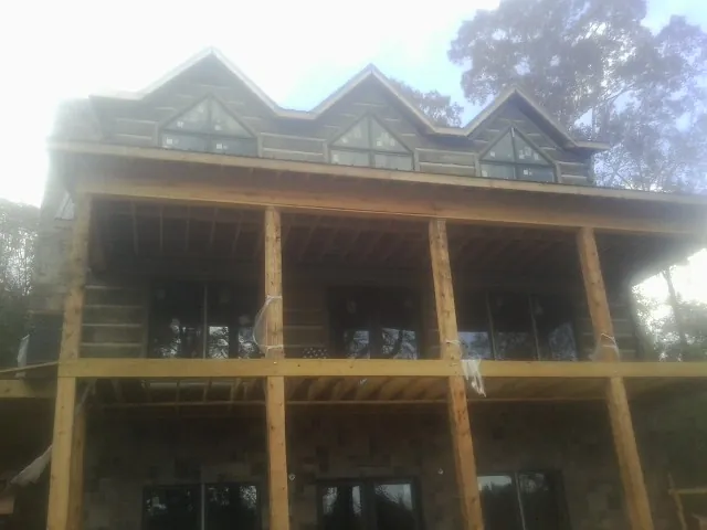 Dormers and porch framing on a large log home under construction — Roof Coating work by our crew in Adams